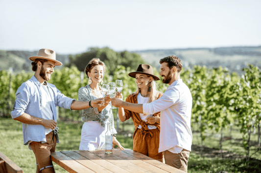 Group of guests in smart casual outfits enjoying a wine tasting at an outdoor vineyard table