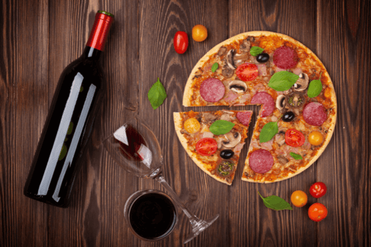 Pizza and red wine pairing with a bottle, wine glass, and freshly baked pizza on a wooden table