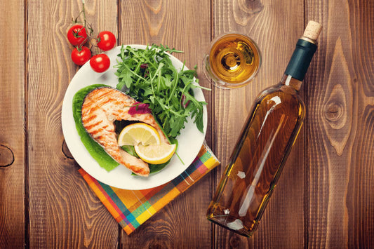 Salmon dish served with vegetables and a glass of wine on a wooden table
