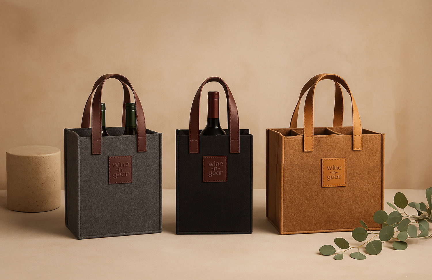 Three wine bags in gray, black, and brown on a beige background with a small plant.
